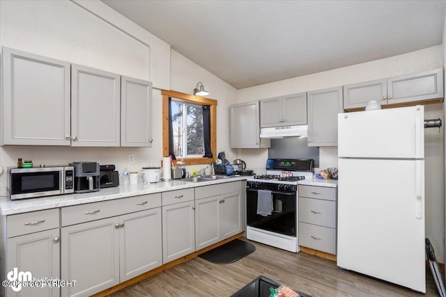 kitchen with sink, gas stove, light hardwood / wood-style flooring, gray cabinets, and white fridge