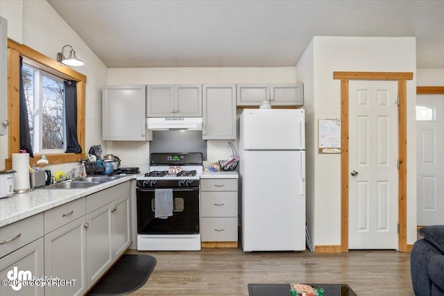 kitchen featuring sink, gas stove, gray cabinetry, white fridge, and light hardwood / wood-style floors