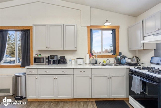 kitchen with lofted ceiling, gas range oven, sink, and plenty of natural light