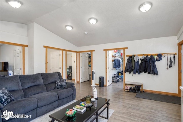 living room with hardwood / wood-style flooring, lofted ceiling, and a textured ceiling