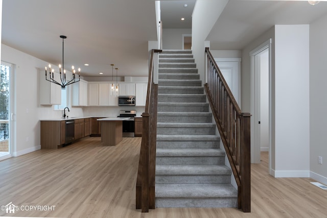 stairway featuring wood-type flooring, sink, and an inviting chandelier