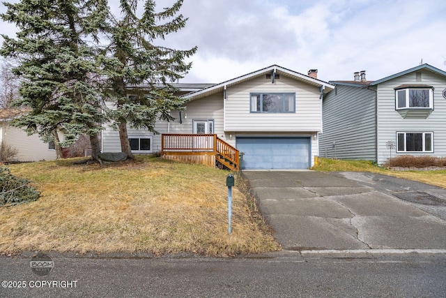 split foyer home with an attached garage, aphalt driveway, and a front yard