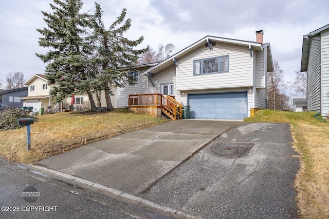 raised ranch with a chimney, an attached garage, aphalt driveway, and a front yard
