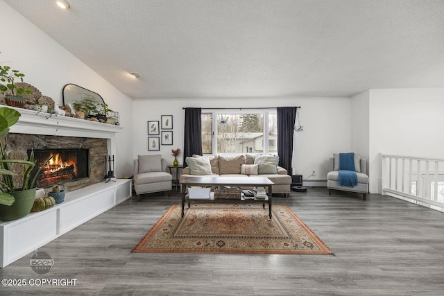living area with a stone fireplace, wood finished floors, a textured ceiling, and a baseboard radiator