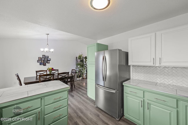 kitchen featuring tasteful backsplash, freestanding refrigerator, a chandelier, white cabinetry, and dark wood-type flooring