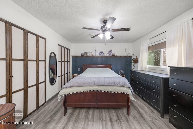 bedroom featuring wood finished floors, a textured ceiling, and a ceiling fan