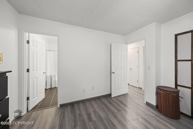 unfurnished bedroom with baseboards, wood finished floors, and a textured ceiling