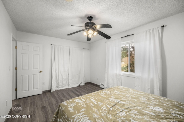bedroom with a baseboard radiator, baseboards, wood finished floors, and a textured ceiling