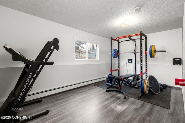 exercise area with a baseboard heating unit, wood finished floors, and a textured ceiling
