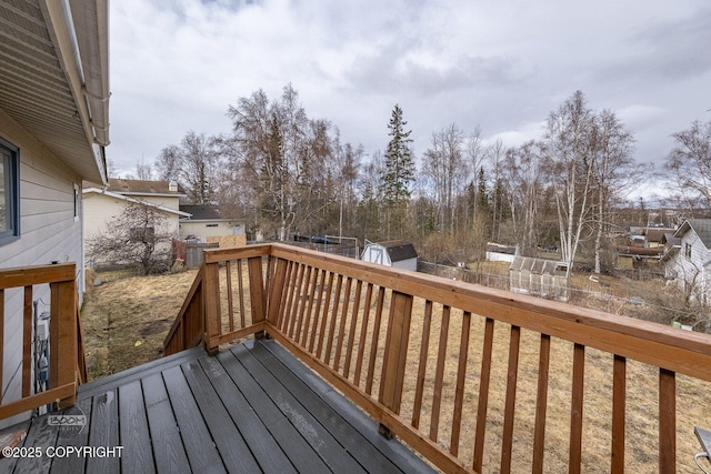 deck with a fenced backyard, an outdoor structure, and a storage shed