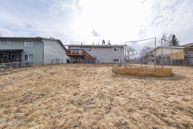 rear view of property featuring stairway, fence, a deck, and a vegetable garden