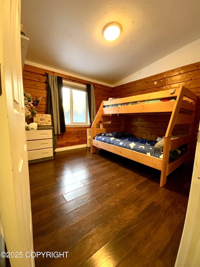 unfurnished bedroom featuring lofted ceiling, dark hardwood / wood-style flooring, and wood walls