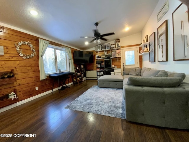 living room with lofted ceiling, dark hardwood / wood-style floors, ceiling fan, and wood walls