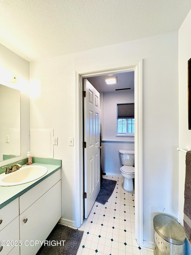 bathroom featuring vanity, toilet, and a textured ceiling