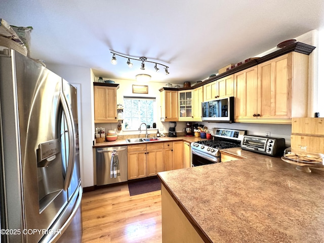 kitchen featuring rail lighting, sink, light brown cabinets, appliances with stainless steel finishes, and light hardwood / wood-style floors