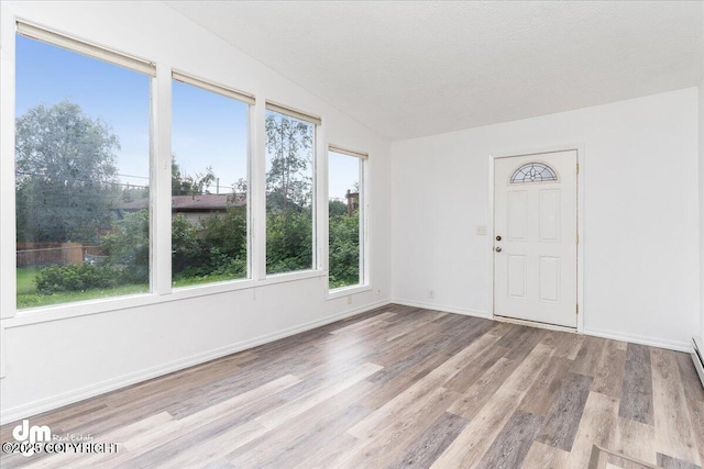 empty room featuring vaulted ceiling, a textured ceiling, and light wood-type flooring