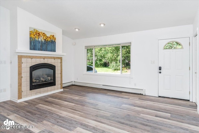 unfurnished living room featuring wood-type flooring, lofted ceiling, a fireplace, and baseboard heating