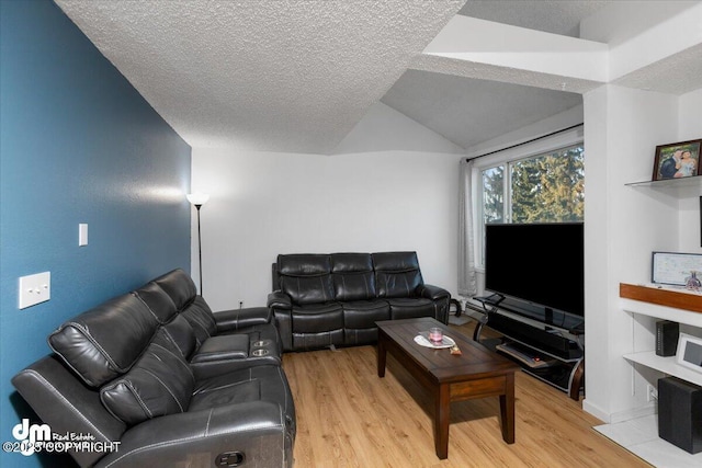 living room with lofted ceiling, a textured ceiling, and light wood-type flooring