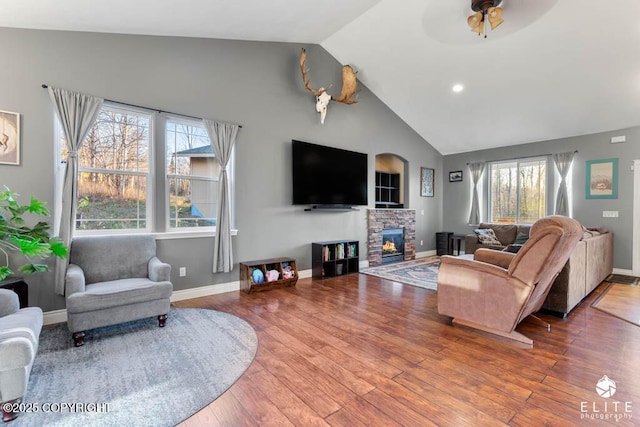 living room featuring hardwood / wood-style flooring, ceiling fan, a fireplace, and high vaulted ceiling