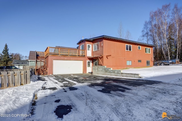 view of front of house featuring fence, a garage, driveway, a wooden deck, and stairs