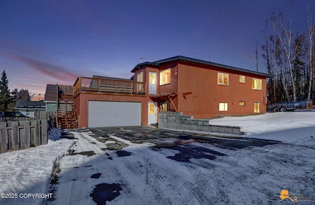 view of front of house featuring a deck, a garage, fence, stairs, and driveway