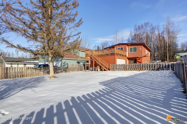 snow covered property featuring fence private yard, stairway, and a wooden deck