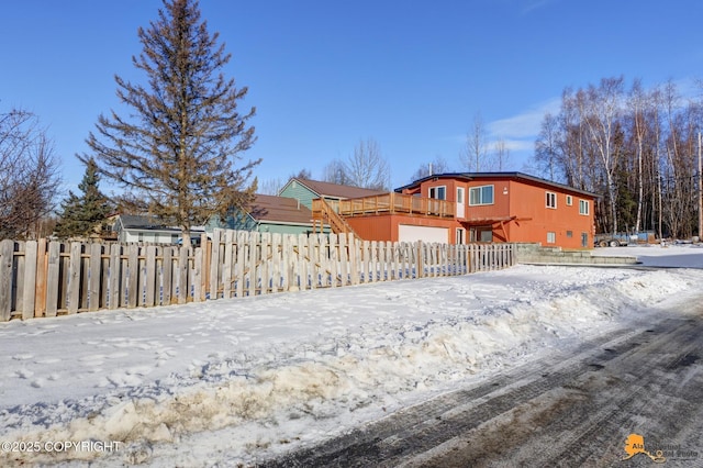 snow covered property with fence and a wooden deck