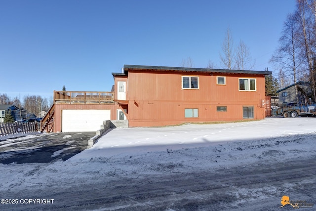 view of front of house with a wooden deck, fence, driveway, and an attached garage