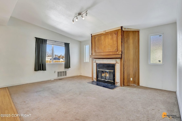 unfurnished living room featuring carpet floors, lofted ceiling, visible vents, and a fireplace