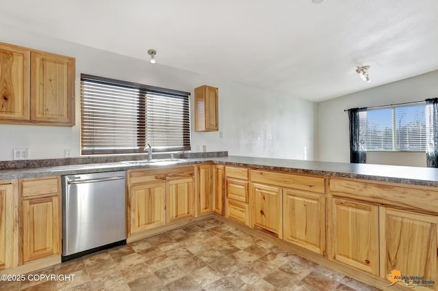 kitchen with dishwasher, dark countertops, a peninsula, light brown cabinetry, and a sink