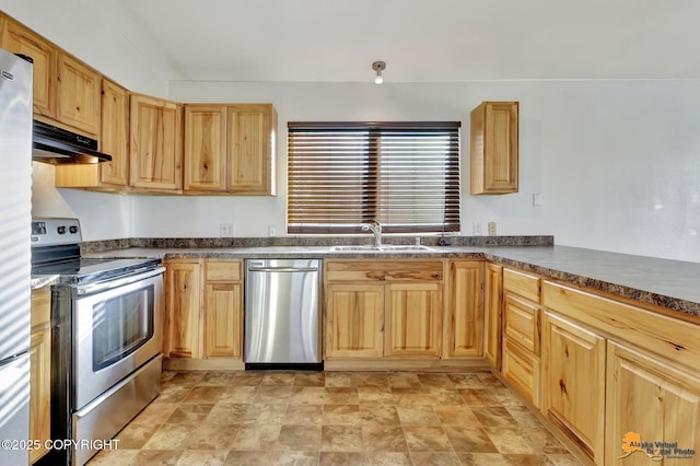 kitchen with dark countertops, under cabinet range hood, stainless steel appliances, and a sink