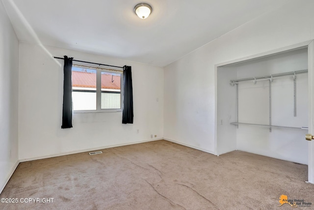 unfurnished bedroom with a closet, carpet, and visible vents