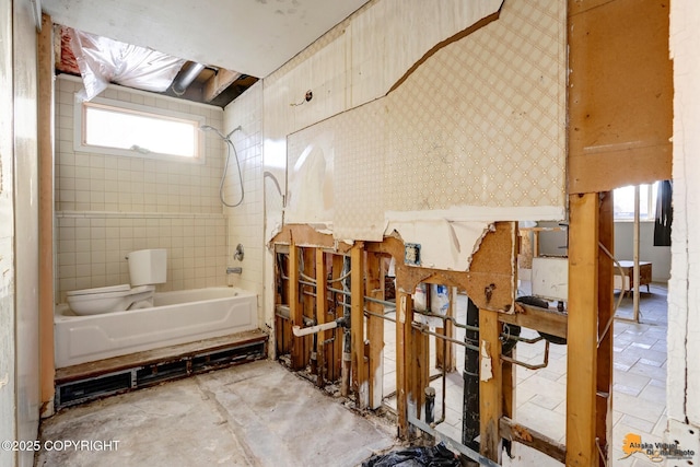 bathroom with bathtub / shower combination, toilet, and wallpapered walls