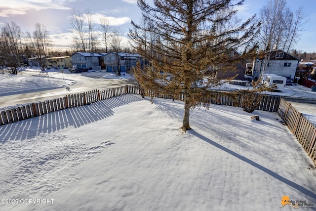 yard covered in snow with a residential view and fence