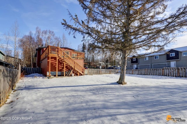 yard layered in snow featuring stairs, a deck, and a fenced backyard