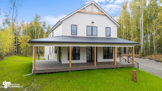 rear view of property featuring a lawn and covered porch