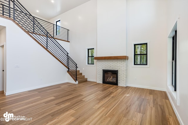 unfurnished living room featuring a towering ceiling, a fireplace, and light wood-type flooring