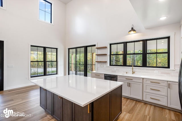 kitchen with dishwasher, a center island, dark brown cabinetry, and light hardwood / wood-style flooring