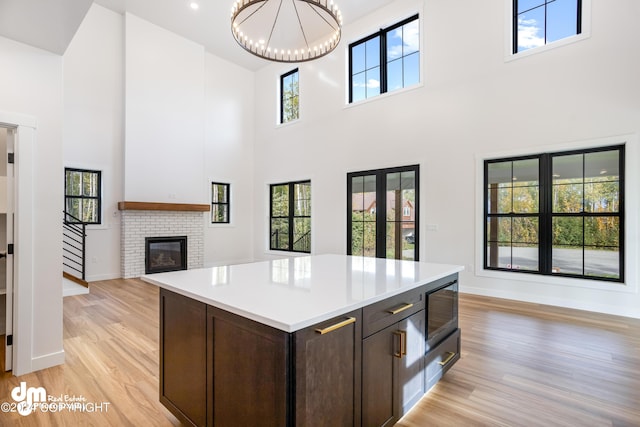 kitchen featuring an inviting chandelier, a center island, dark brown cabinetry, a fireplace, and built in microwave