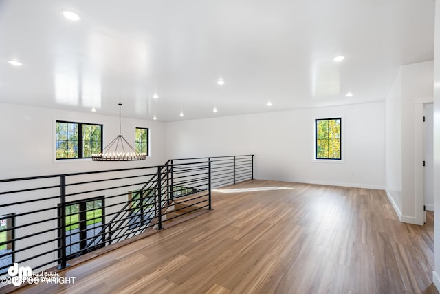 unfurnished room featuring plenty of natural light, a chandelier, and light hardwood / wood-style floors