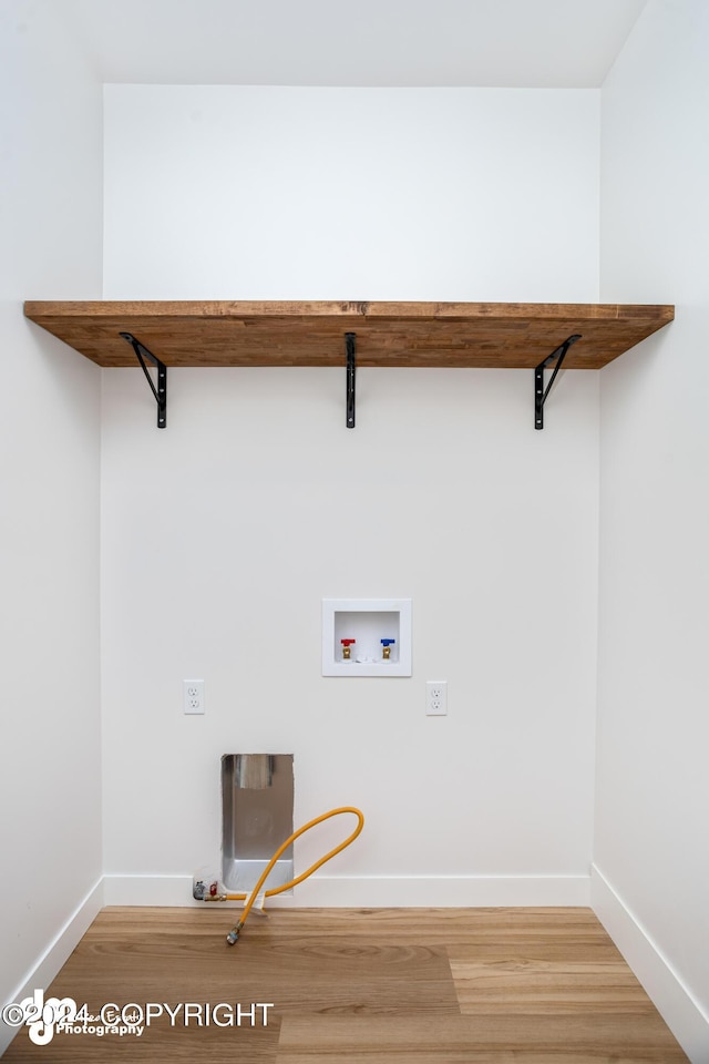 clothes washing area featuring gas dryer hookup, hookup for a washing machine, and hardwood / wood-style flooring