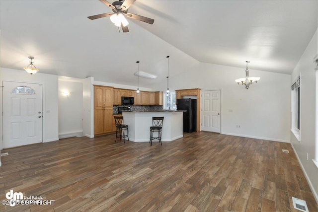 kitchen featuring decorative light fixtures, black appliances, a center island, and a kitchen bar