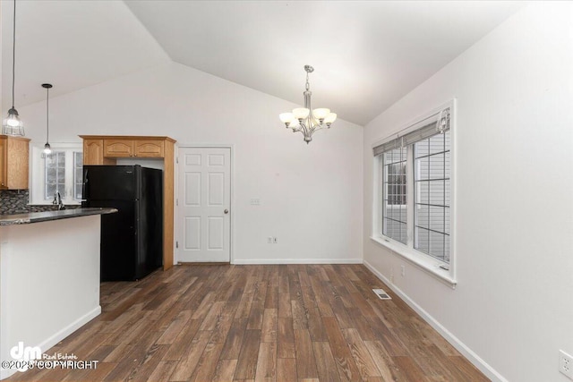 kitchen featuring hanging light fixtures, black refrigerator, an inviting chandelier, and dark hardwood / wood-style flooring