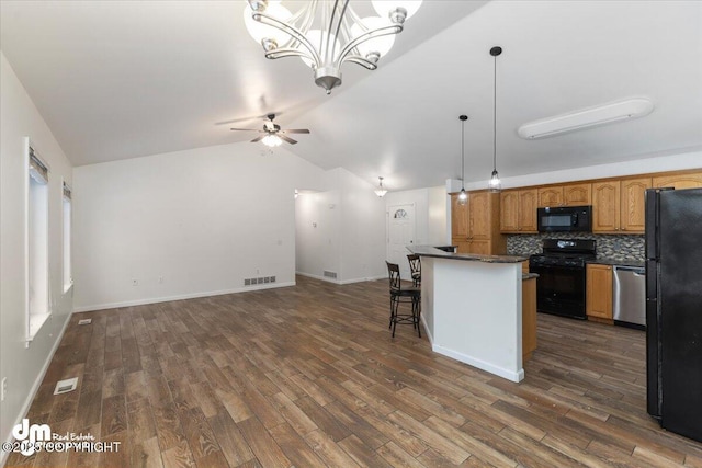 kitchen featuring lofted ceiling, dark hardwood / wood-style floors, a kitchen breakfast bar, pendant lighting, and black appliances