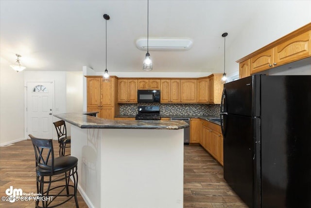 kitchen featuring decorative light fixtures, dark hardwood / wood-style flooring, a kitchen island, and black appliances