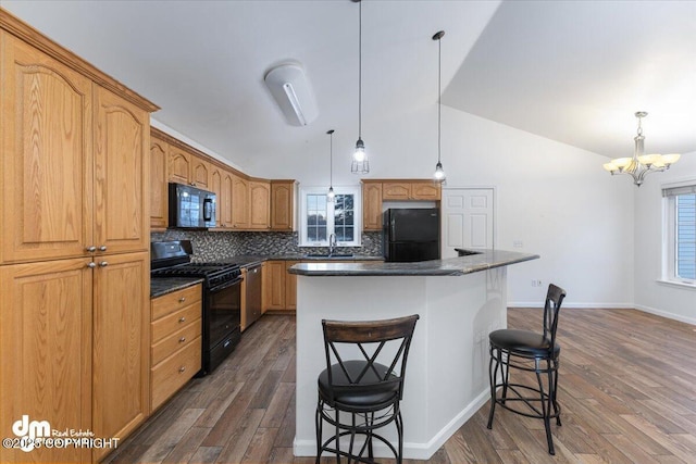 kitchen featuring decorative light fixtures, a center island, a breakfast bar area, and black appliances