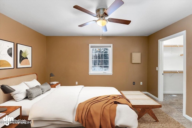 bedroom featuring light carpet, a spacious closet, and ceiling fan