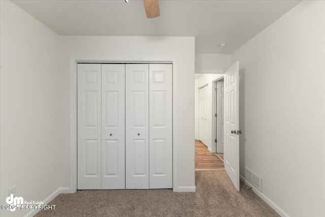 unfurnished bedroom with ceiling fan, a closet, and light carpet