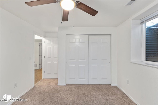 unfurnished bedroom featuring ceiling fan, a closet, and light carpet