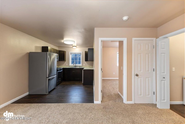 kitchen with dark colored carpet, stove, sink, and stainless steel refrigerator